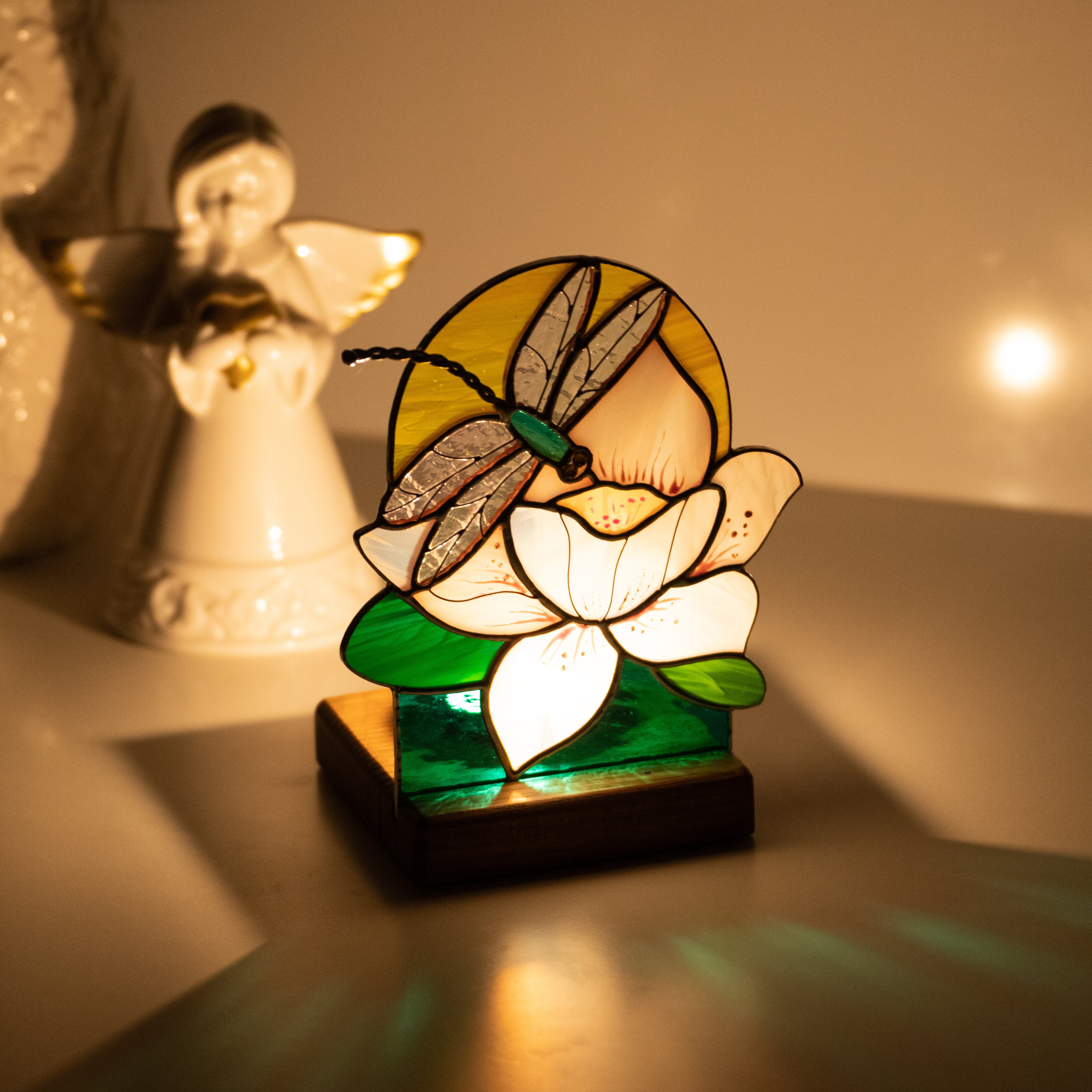 Candle-lit stained glass dragonfly panel in the dark 