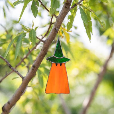Stained glass orange ghost wearing green hat window hanging