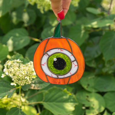 Stained glass pumpkin with the green eye inside window hanging for Halloween decor
