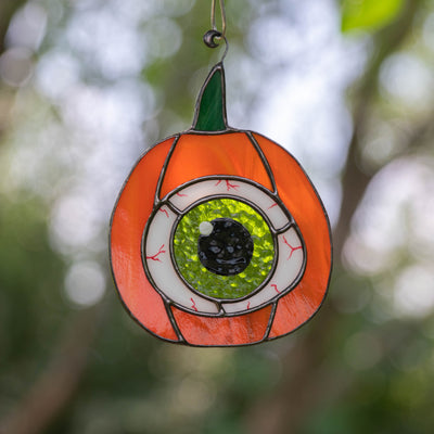 Halloween pumpkin with the green eye inside suncatcher of stained glass