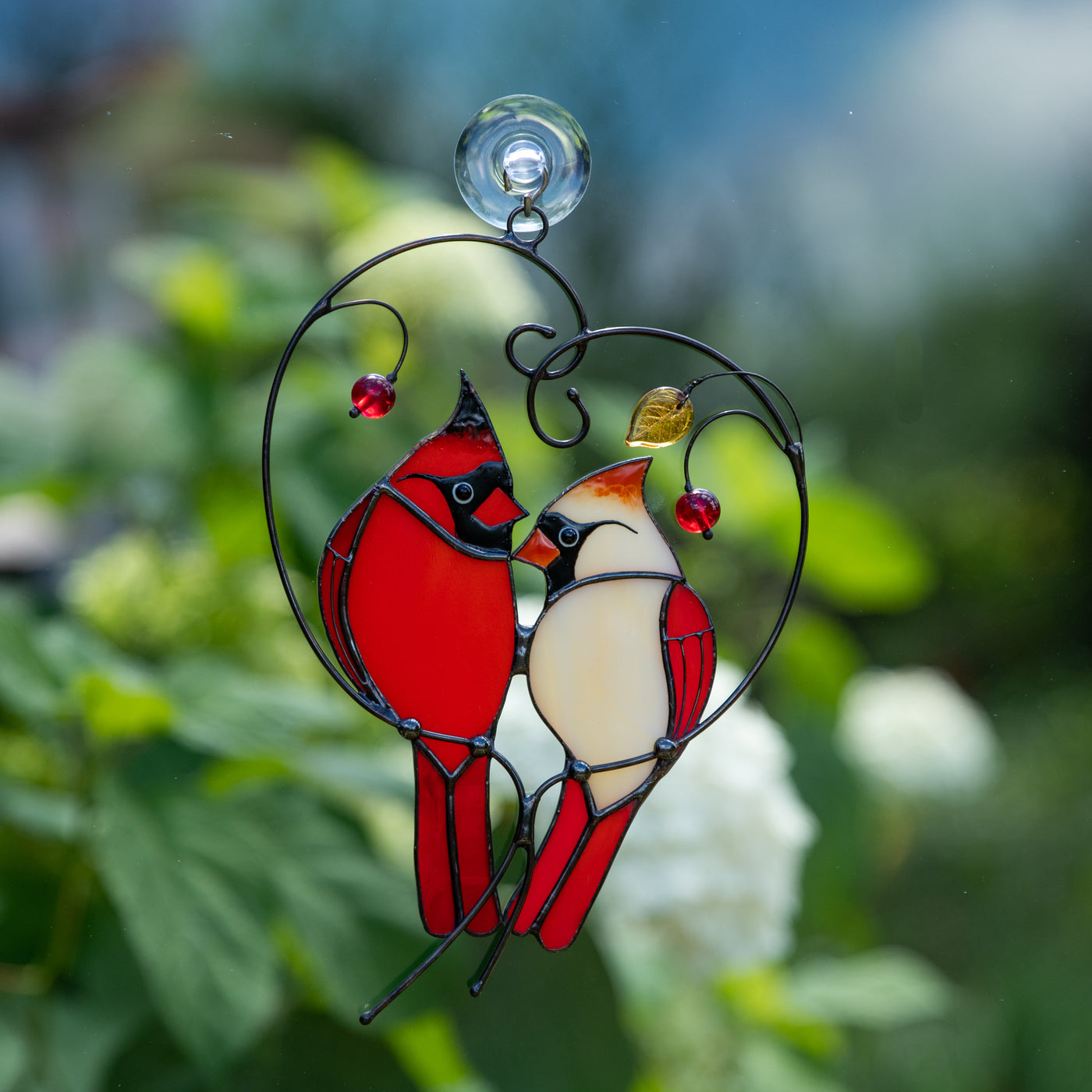 Stained glass of male and female Cardinals sitting on the heart-branch window hanging