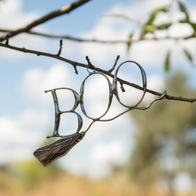Stained glass window hanging of lettering boo on witch's broom