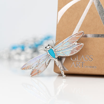Stained glass pin of a blue dragonfly with iridescent wings 