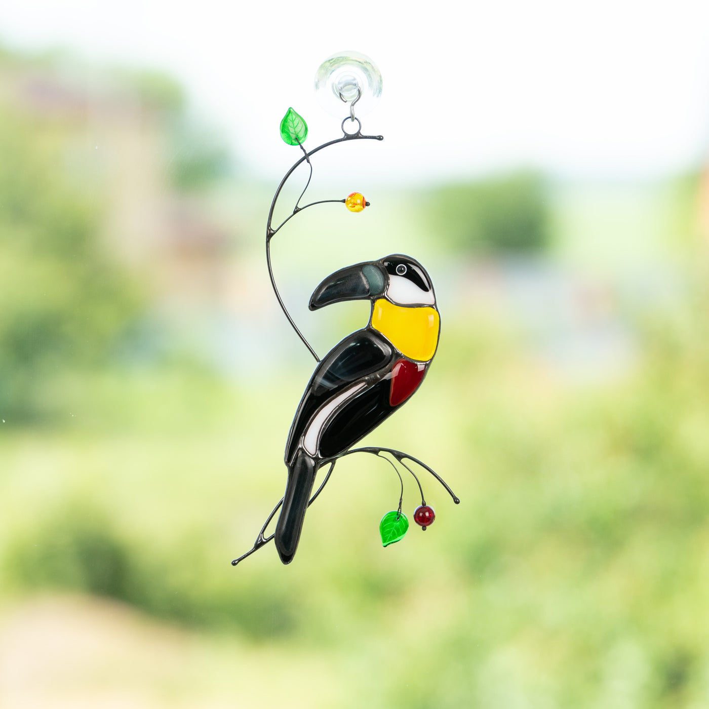 Fusing toucan with yellow neck sitting on the branch with leaves and berries window hanging of stained glass