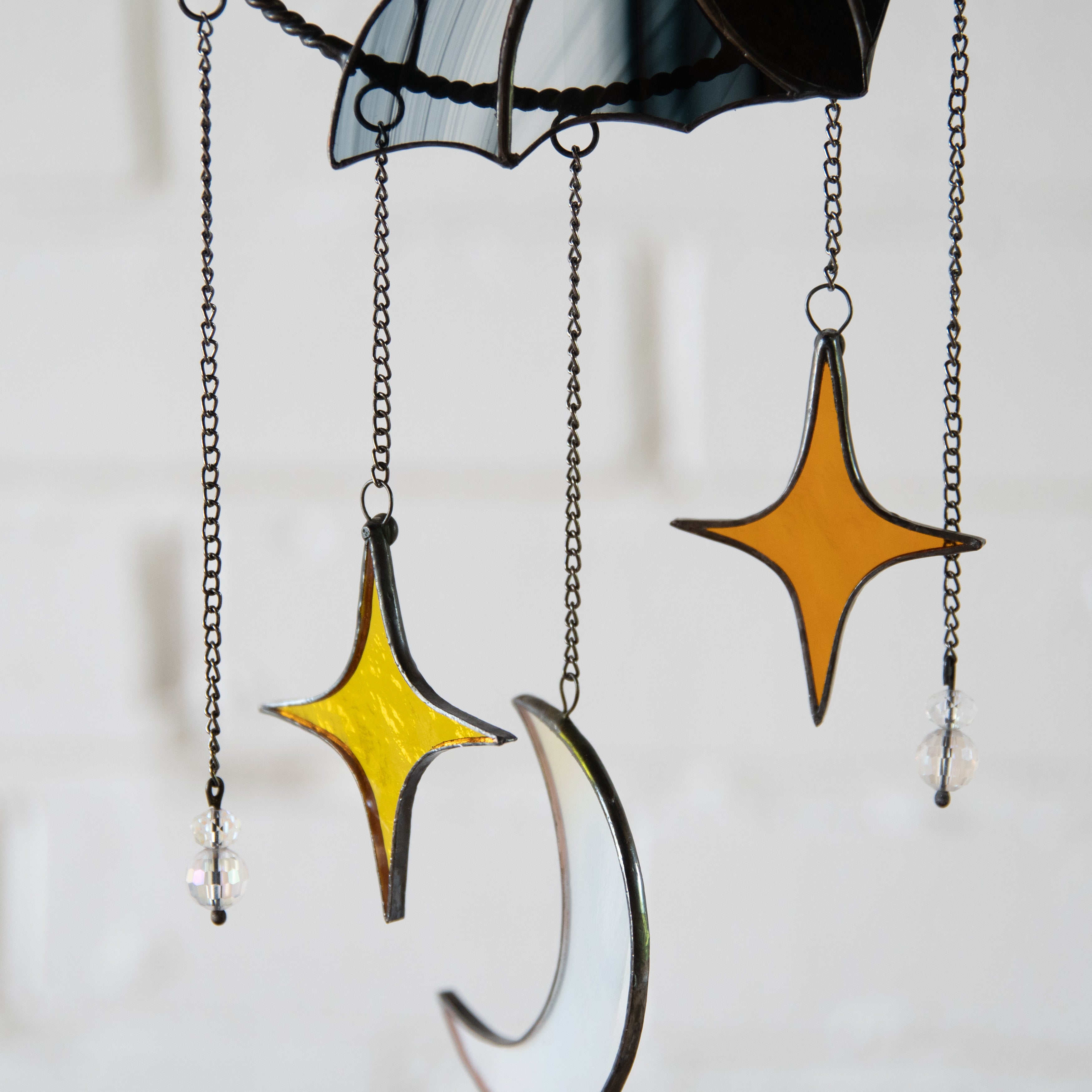 The lower part of a dreamcatcher with stained glass semi-moon and orange stars