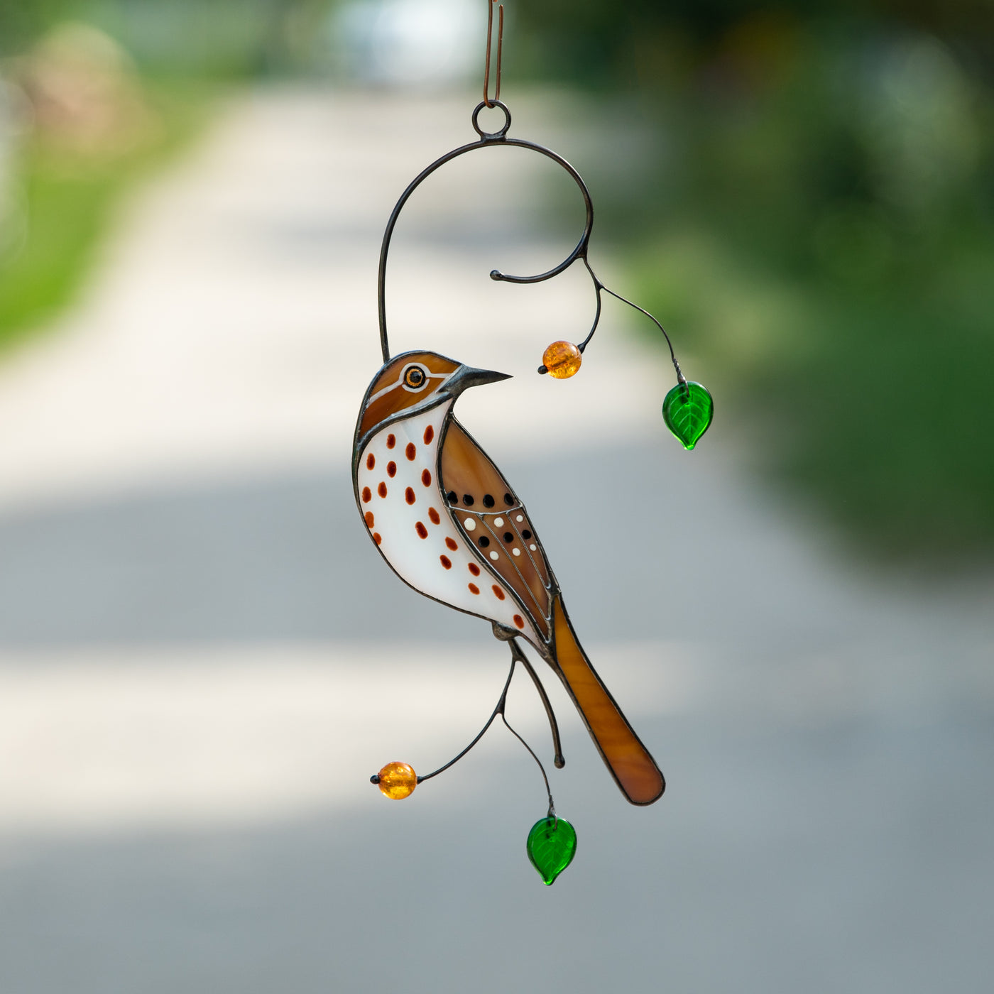 Window hanging of stained glass brown thrasher on the branch