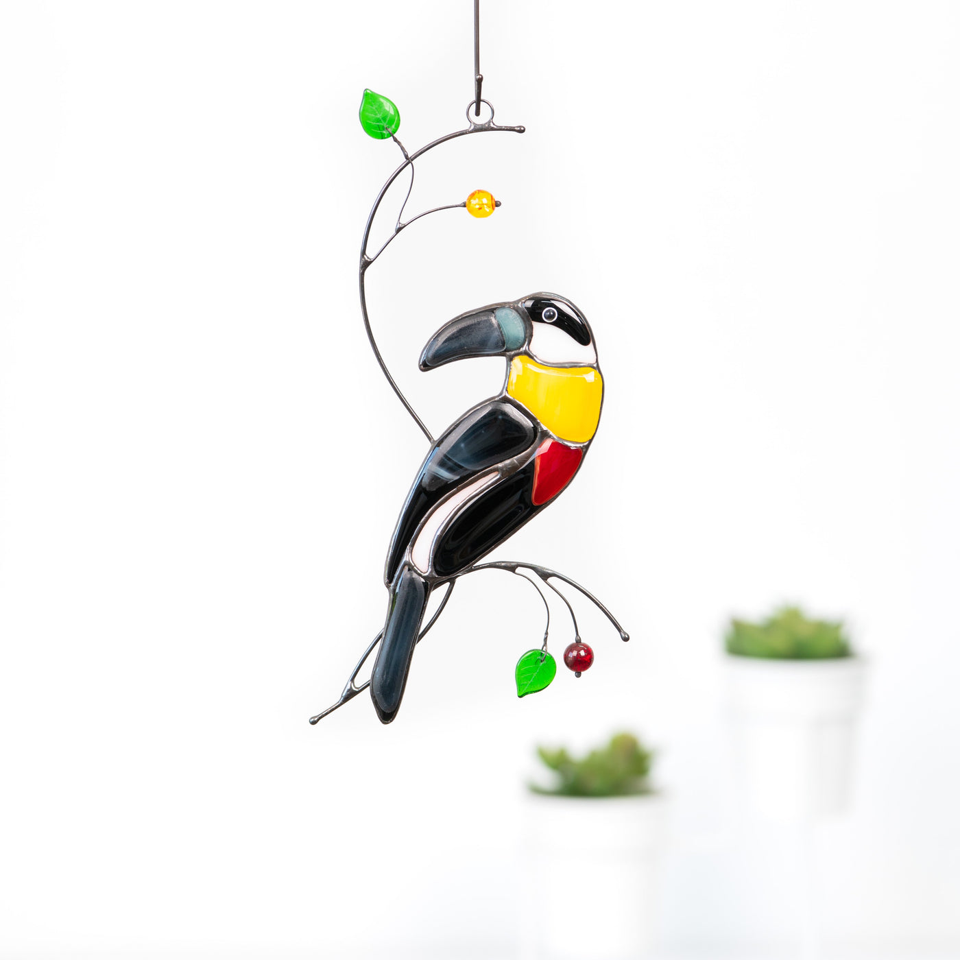 Stained glass toucan with yellow neck sitting on the branch with leaves and berries suncatcher 