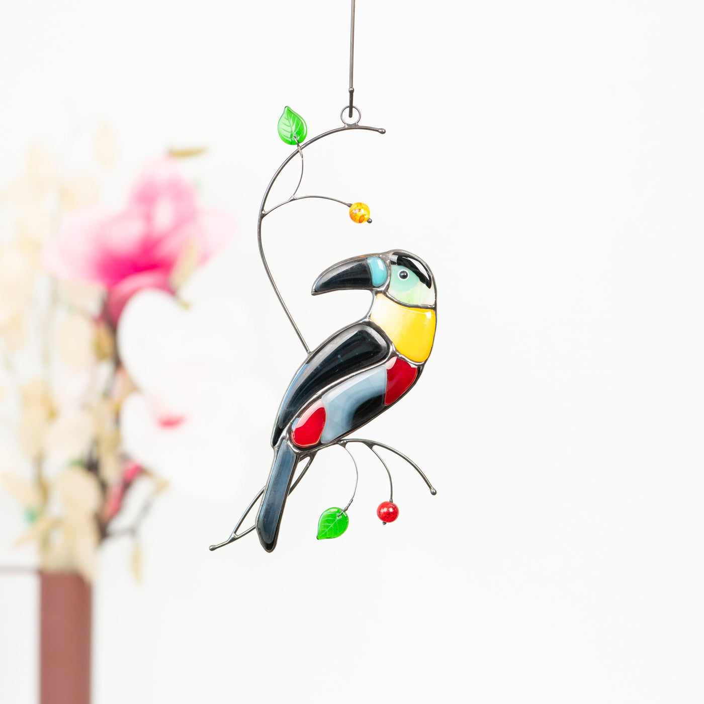Stained glass sitting on the branch with leaves and berries  toucan with bluish head suncatcher