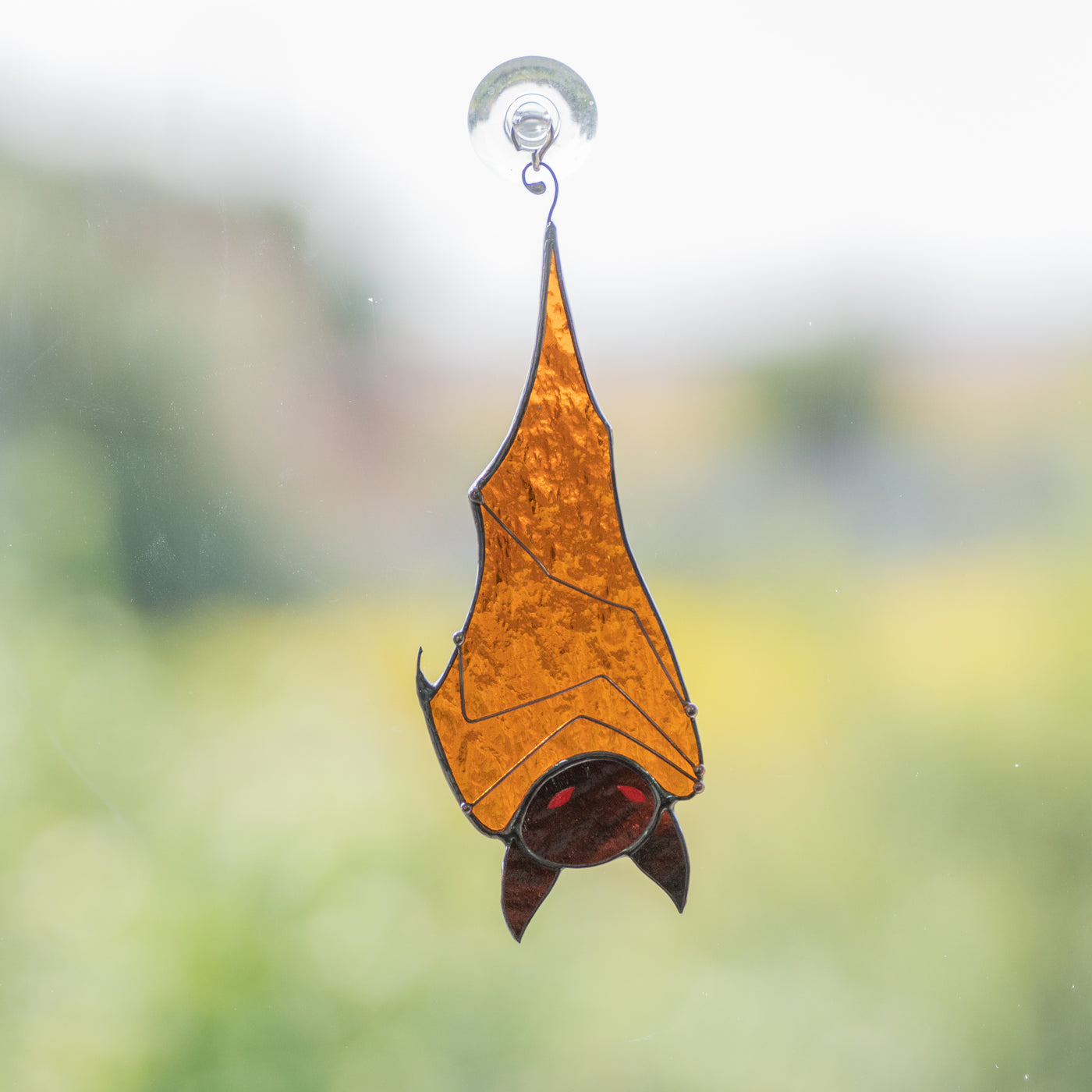 Stained glass brown bat with red eyes hanging down suncatcher