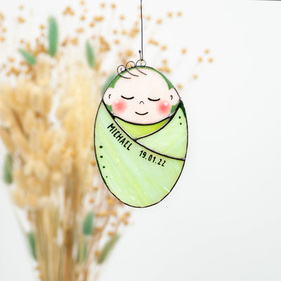 Zoomed stained glass baby in a green blanket window hanging