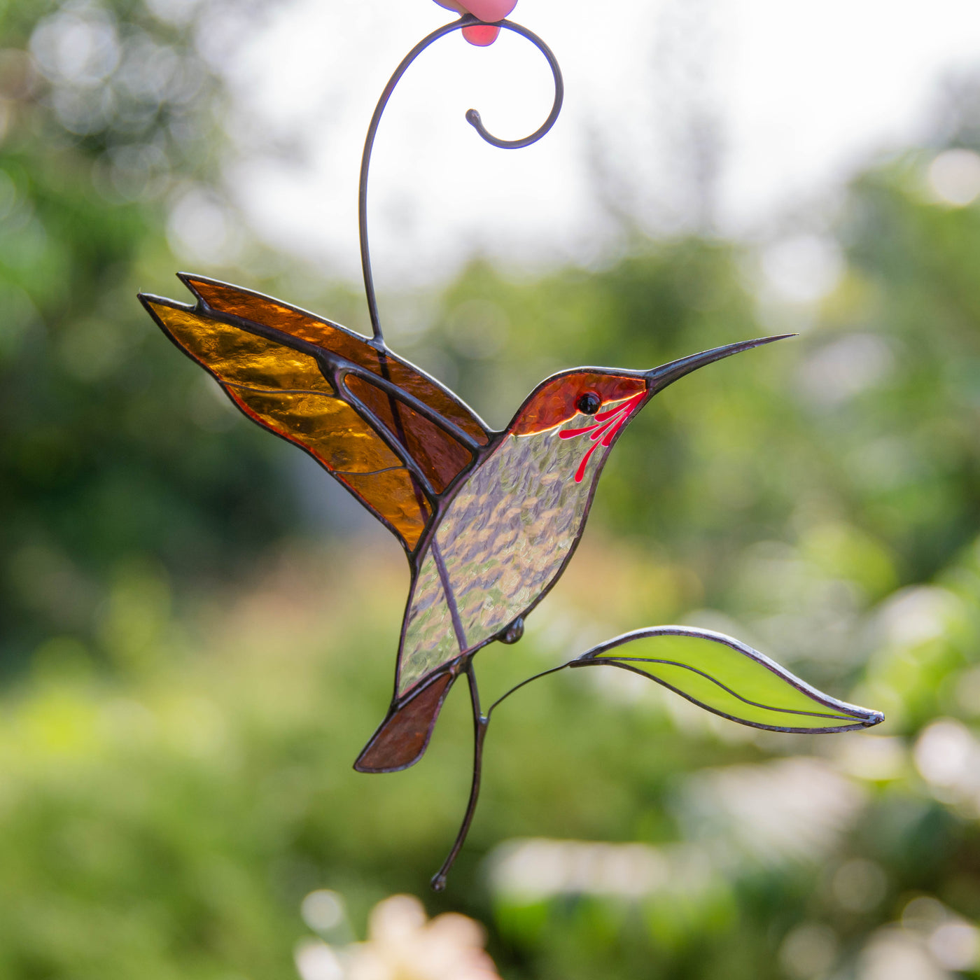 Zoomed stained glass flying hummingbird of golden color
