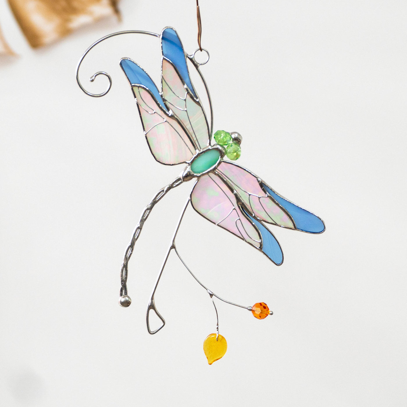 Stained glass blue iridescent-winged dragonfly sitting on the branch window hanging