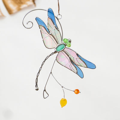 Stained glass blue iridescent-winged dragonfly sitting on the branch window hanging