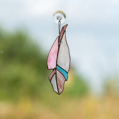 Pink stained glass feather with a blue part window hanging