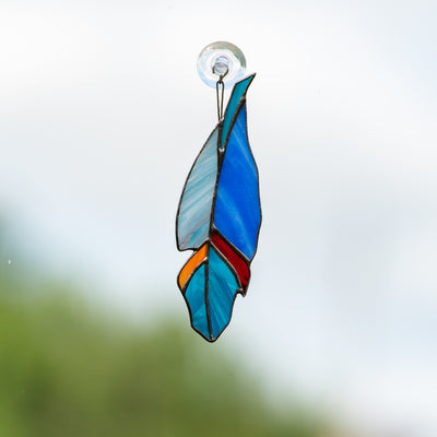 Stained glass blue feather suncatcher with shades of blue, orange and red