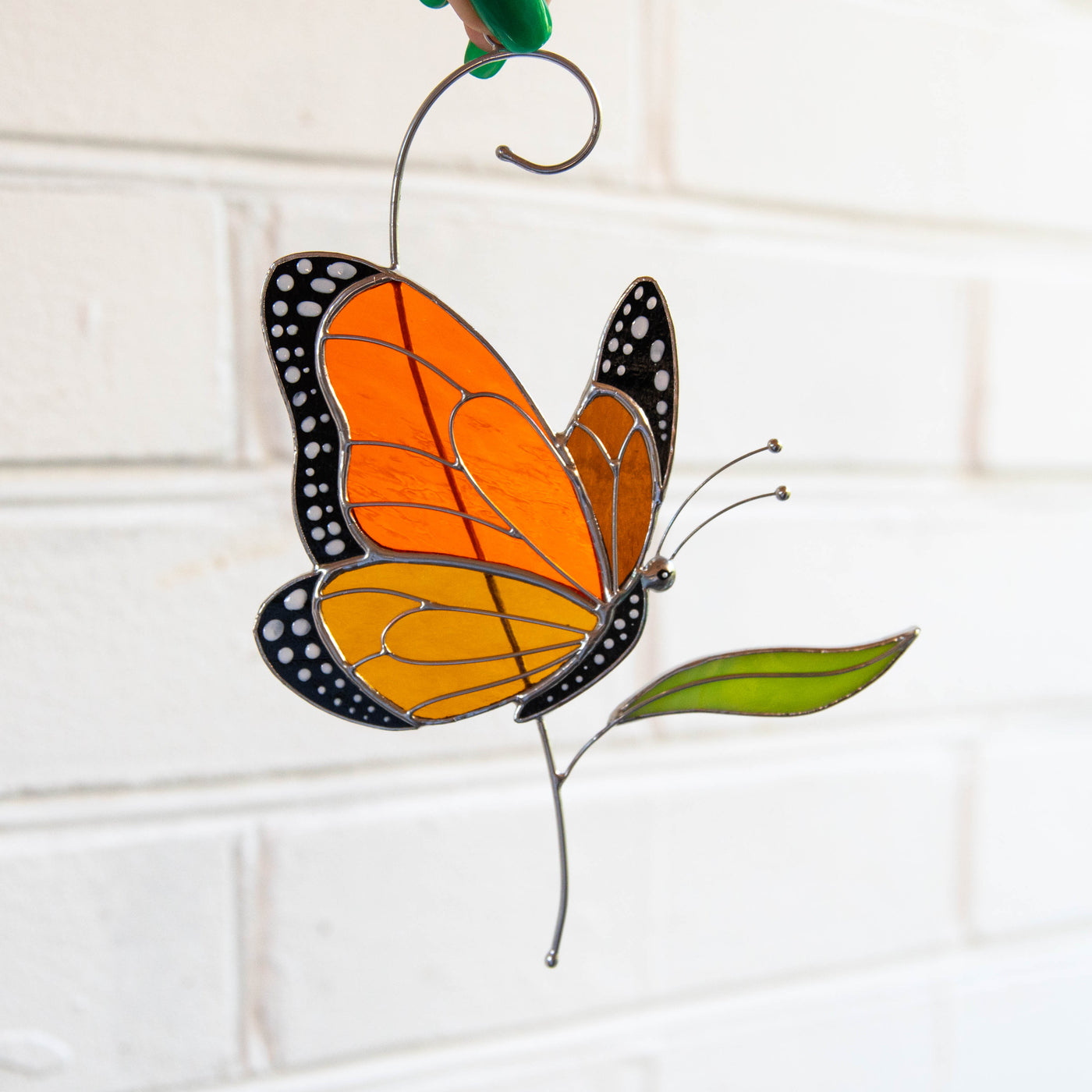 Stained glass monarch butterfly on the branch with leaf sun catcher 