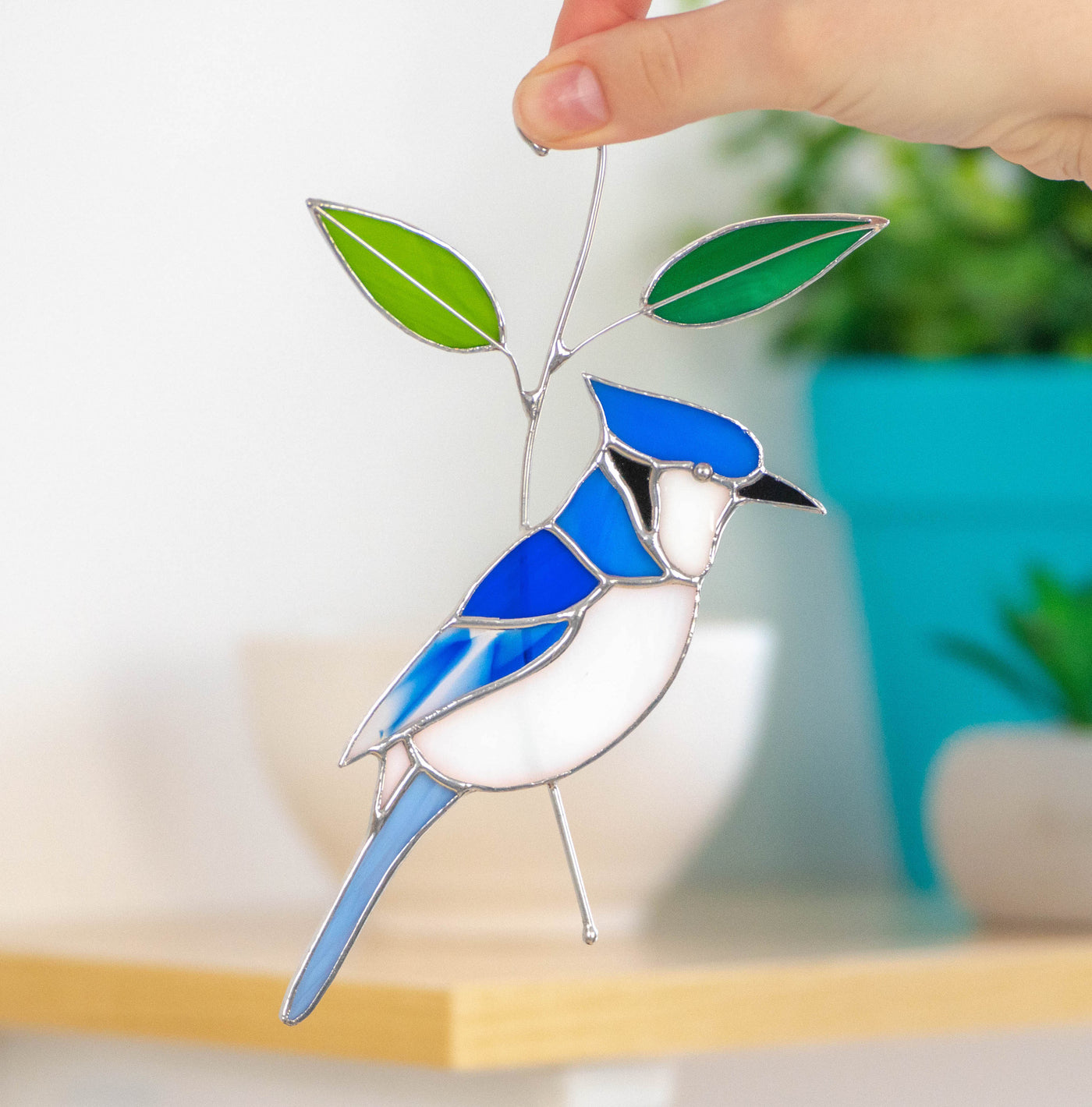 Stained glass blue jay sitting on the branch with leaves suncatcher