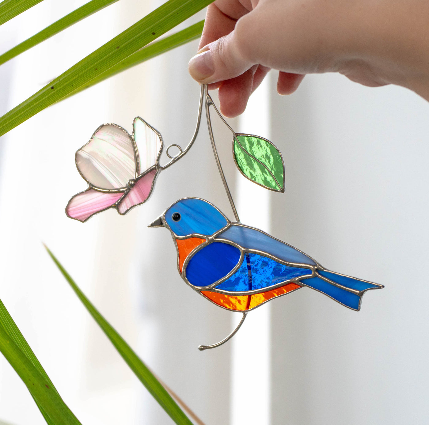 Bluebird suncatcher with pink flower above of stained glass