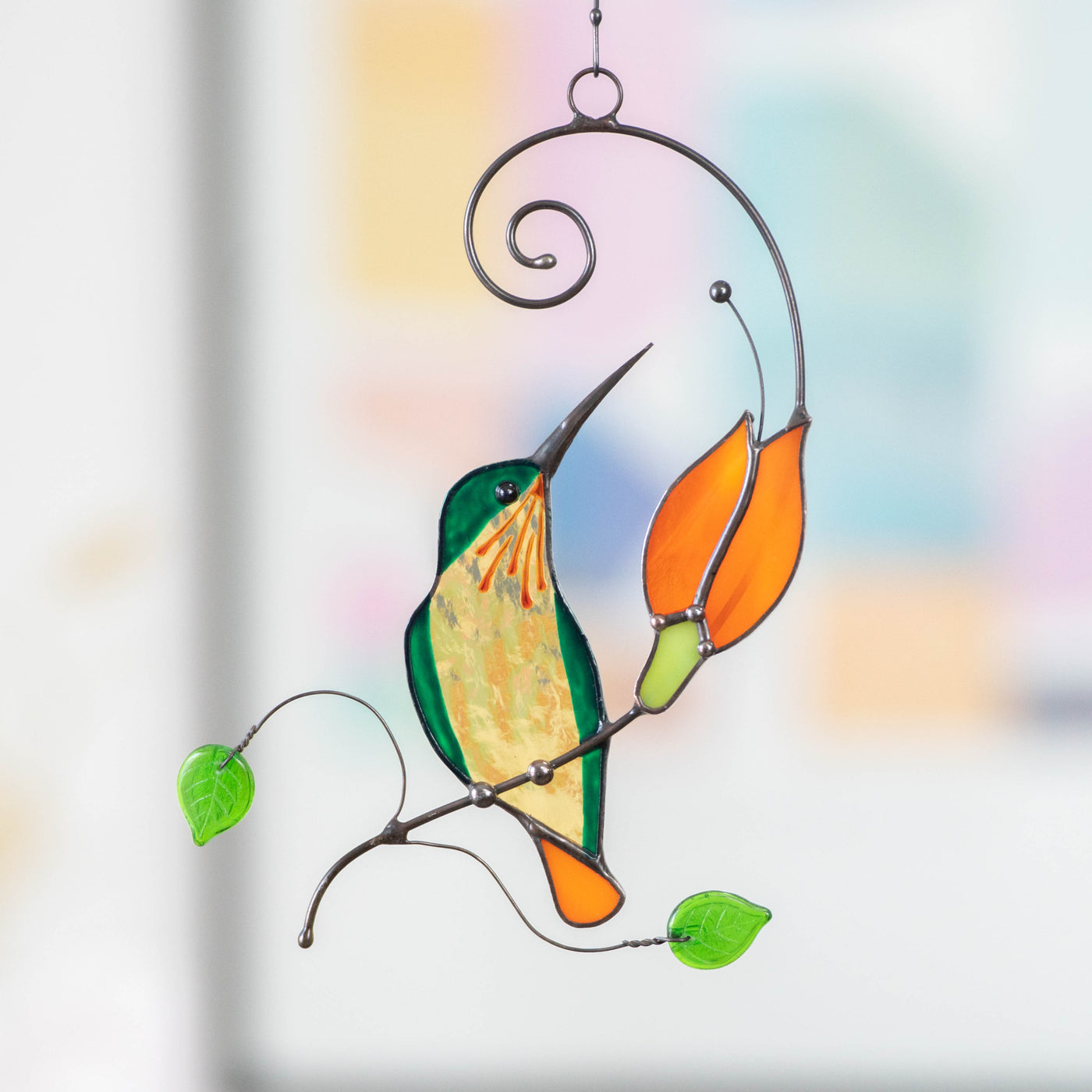 Stained glass hummingbird sitting on the branch with orange flower suncatcher