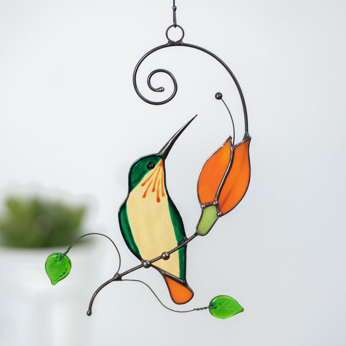 Zoomed stained glass orange and green hummingbird suncatcher