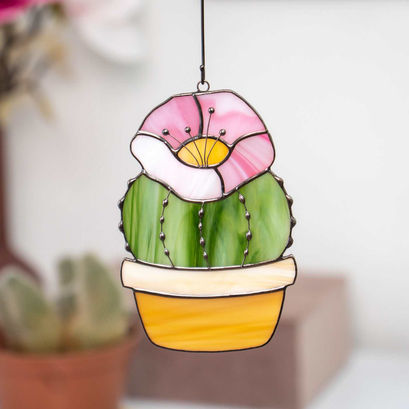 Stained glass window hanging of cactus with pink flower on top
