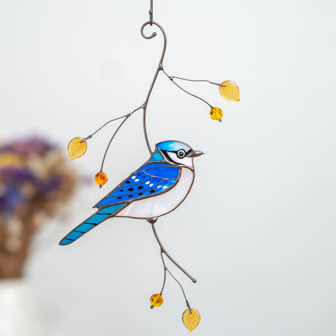 Stained glass wind hanging of a blue jay bird on the branch 