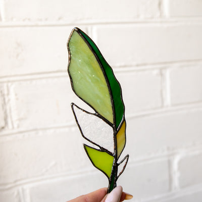 Suncatcher of a stained glass green feather with clear parts