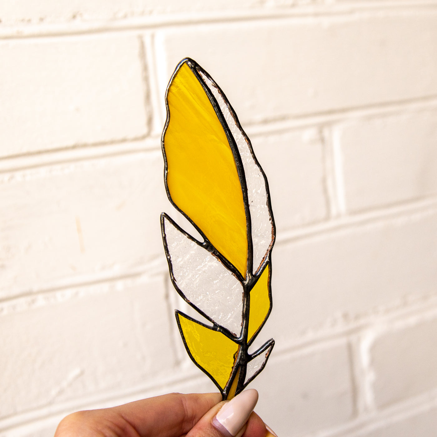 Suncatcher of a stained glass yellow feather with clear parts