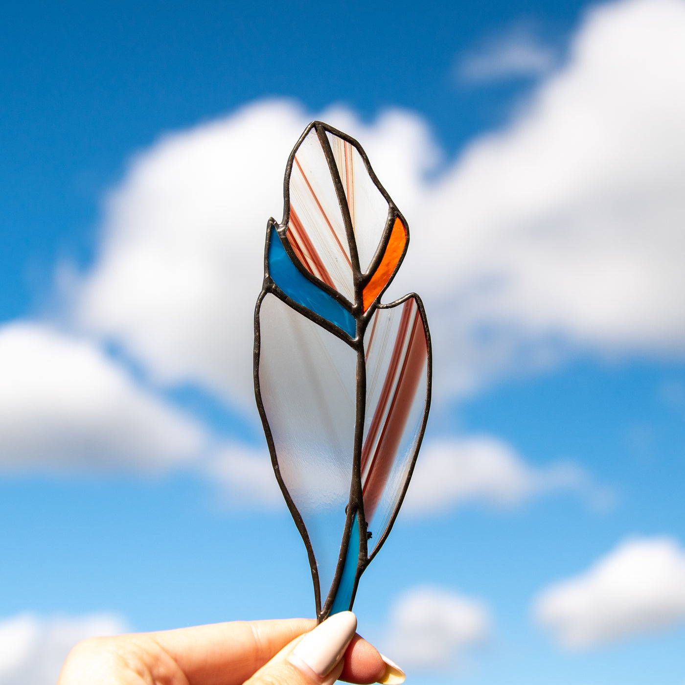 Stained glass clear feather suncatcher with blotchiness and blue and orange parts