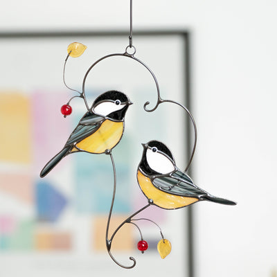 Couple of chickadees sitting on the branch window hanging of stained glass