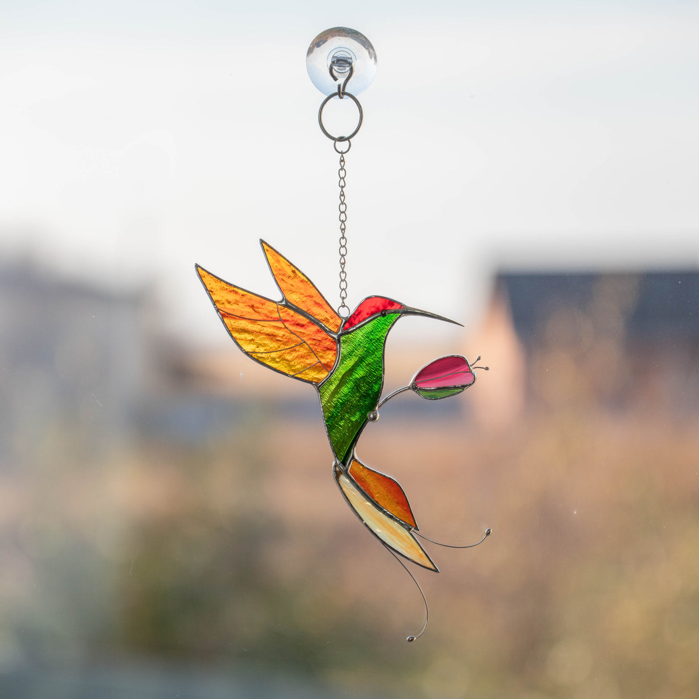 Green hummingbird with orange wings and tail suncatcher of stained glass