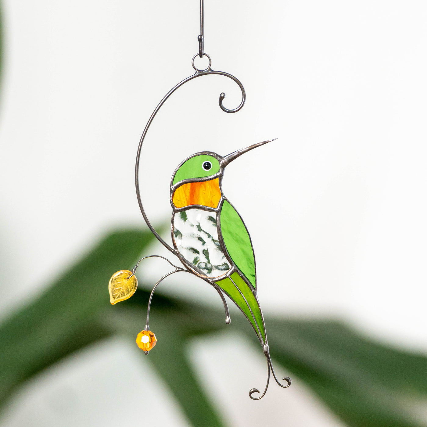 Stained glass window hanging of a hummingbird with transparent belly and orange throat 