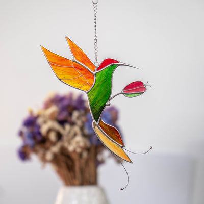 Stained glass suncatcher of green hummingbird with orange wings and tail