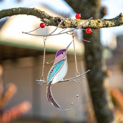 Purple hummingbird with white belly on the swing suncatcher of stained glass