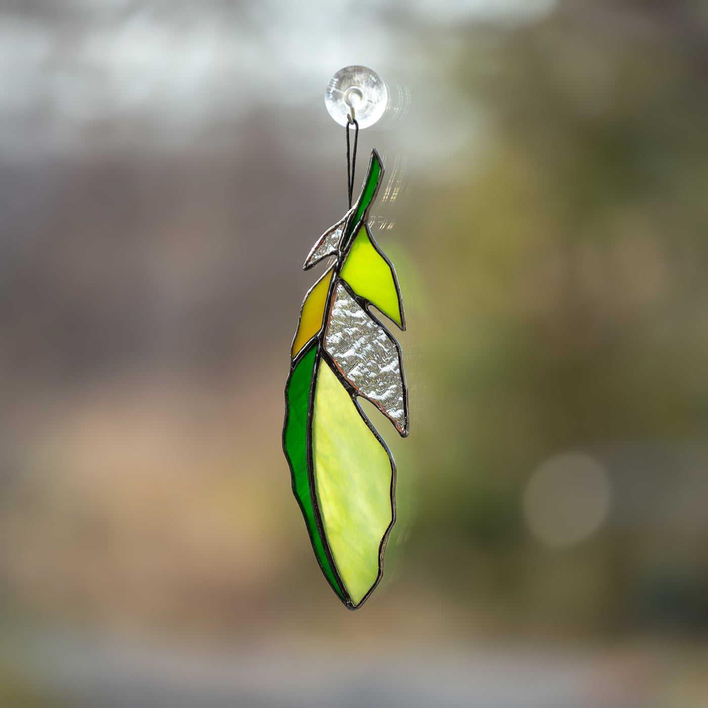 Stained glass feather of green colour with clear parts suncatcher