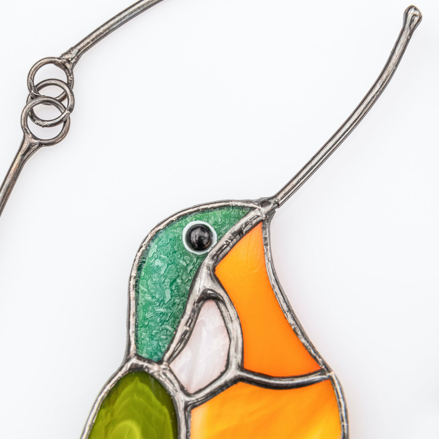 Zoomed stained glass hummingbird of orange and green shades window hanging