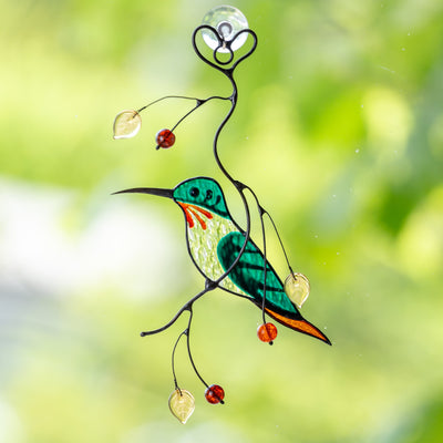 Green male hummingbird window hanging sitting on the branch with leaves and berries