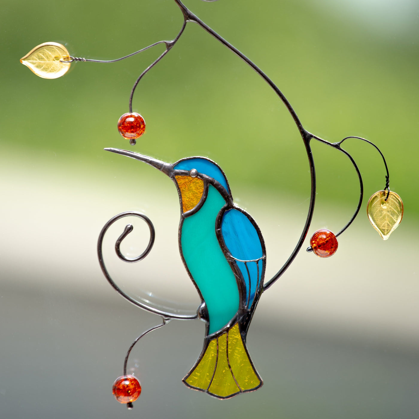 Stained glass bright hummingbird sitting on the branch window hanging