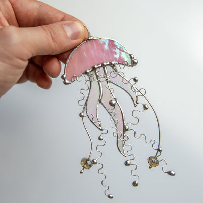 Window hanging of a stained glass pink jellyfish with iridescent tentacles 