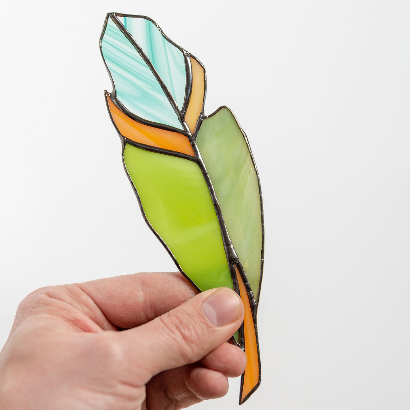 Stained glass green feather with shades of blue and orange suncatcher