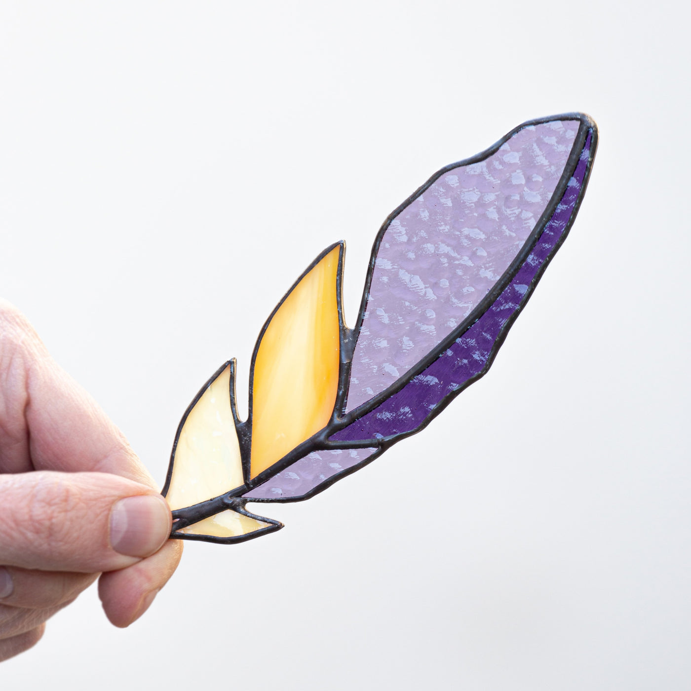 Stained glass feather suncatcher with purple and yellow accents