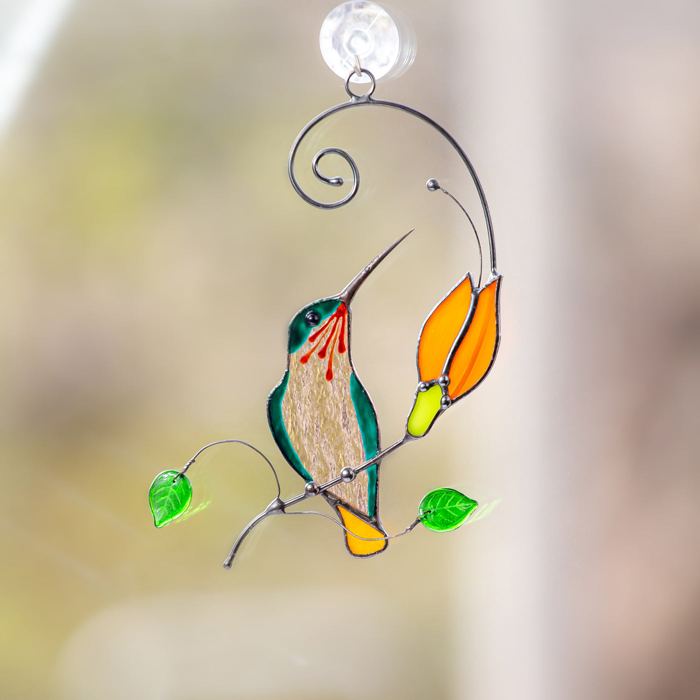 Hummingbird sitting on the branch with orange flower window hanging