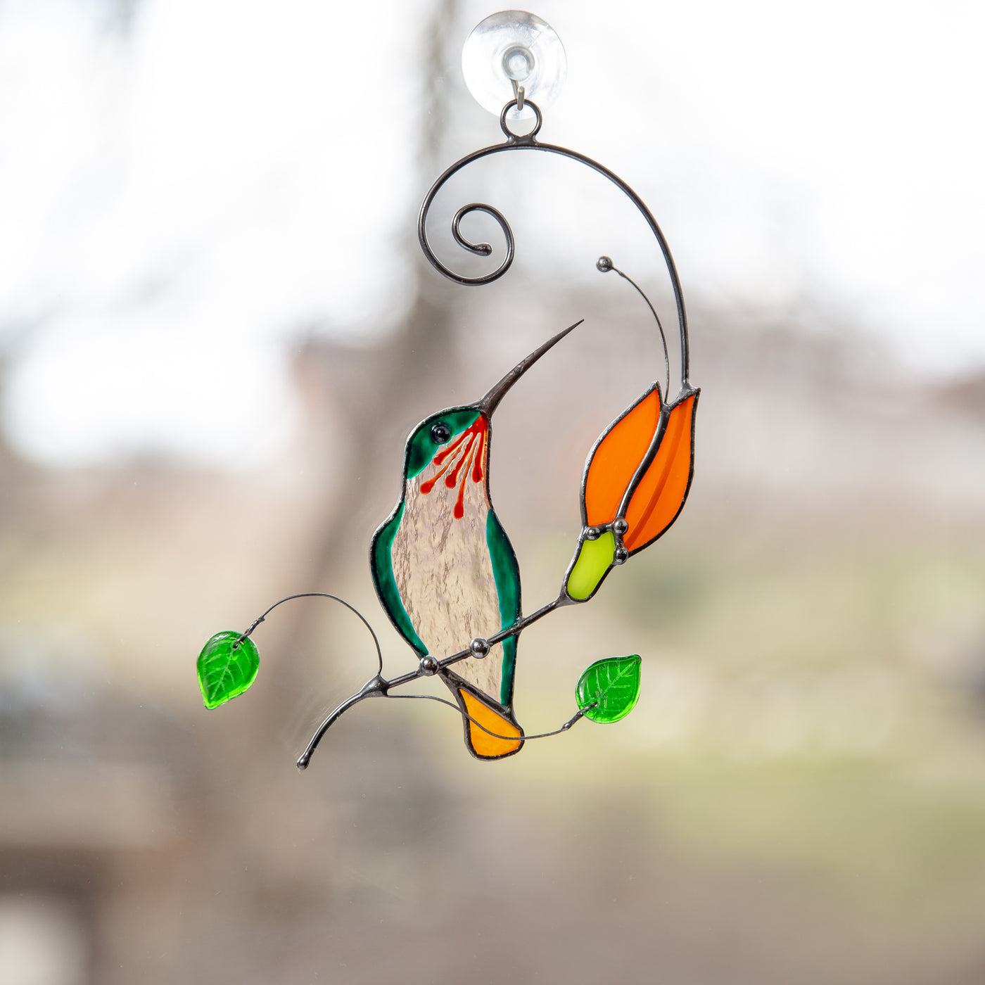 Suncatcher of a stained glass hummingbird on the branch with orange flower