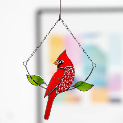 Hanging on the chain red stained glass cardinal suncatcher with green leaves