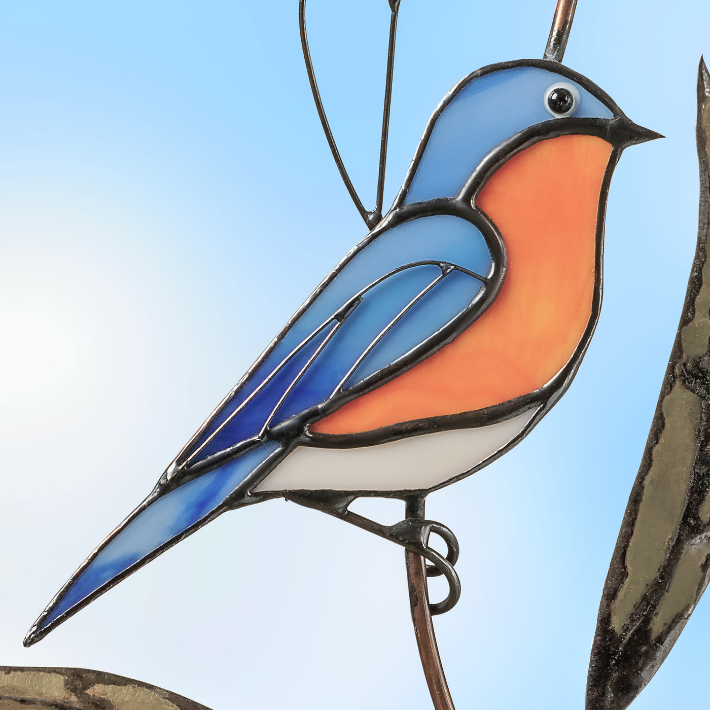 Zoomed stained glass bluebird sitting on the branch suncatcher