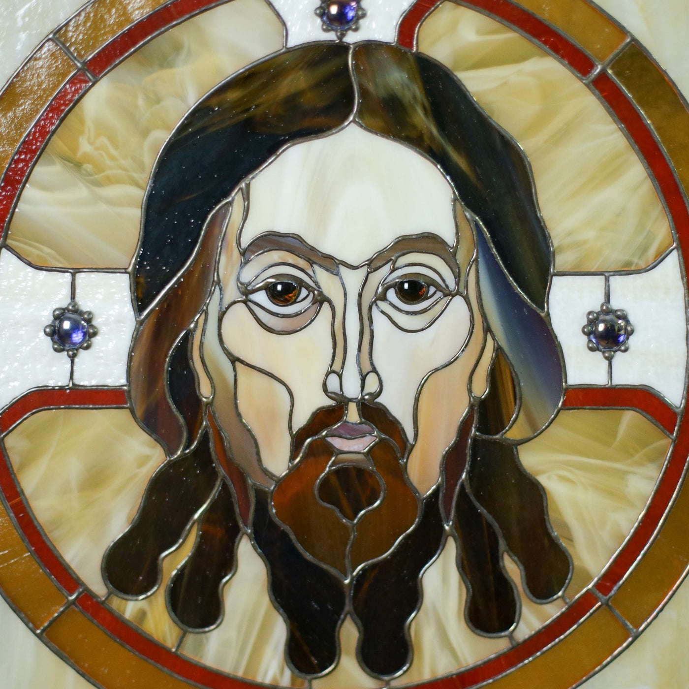 Zoomed stained glass portrait of Jesus Christ in a round with inserted gems panel