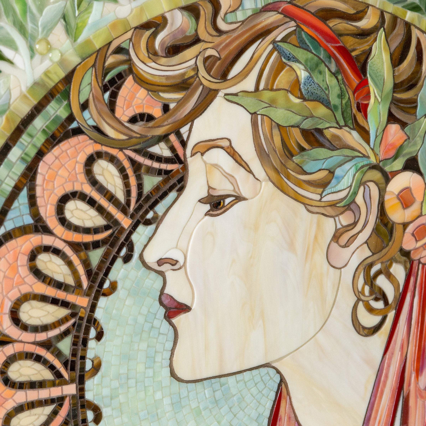 Zoomed stained glass face of a woman in laurel leaves mosaic according to  Alphons Mucha's pattern