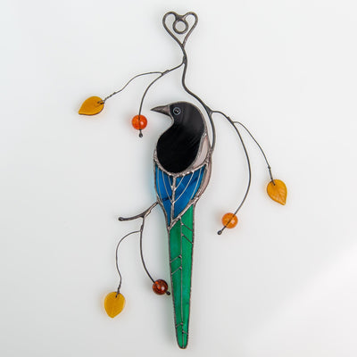 Suncatcher of a stained glass magpie sitting on the branch