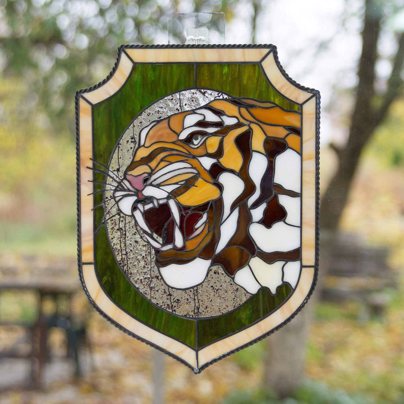 Stained glass panel depicting tiger's head with fangs in an oval and green background