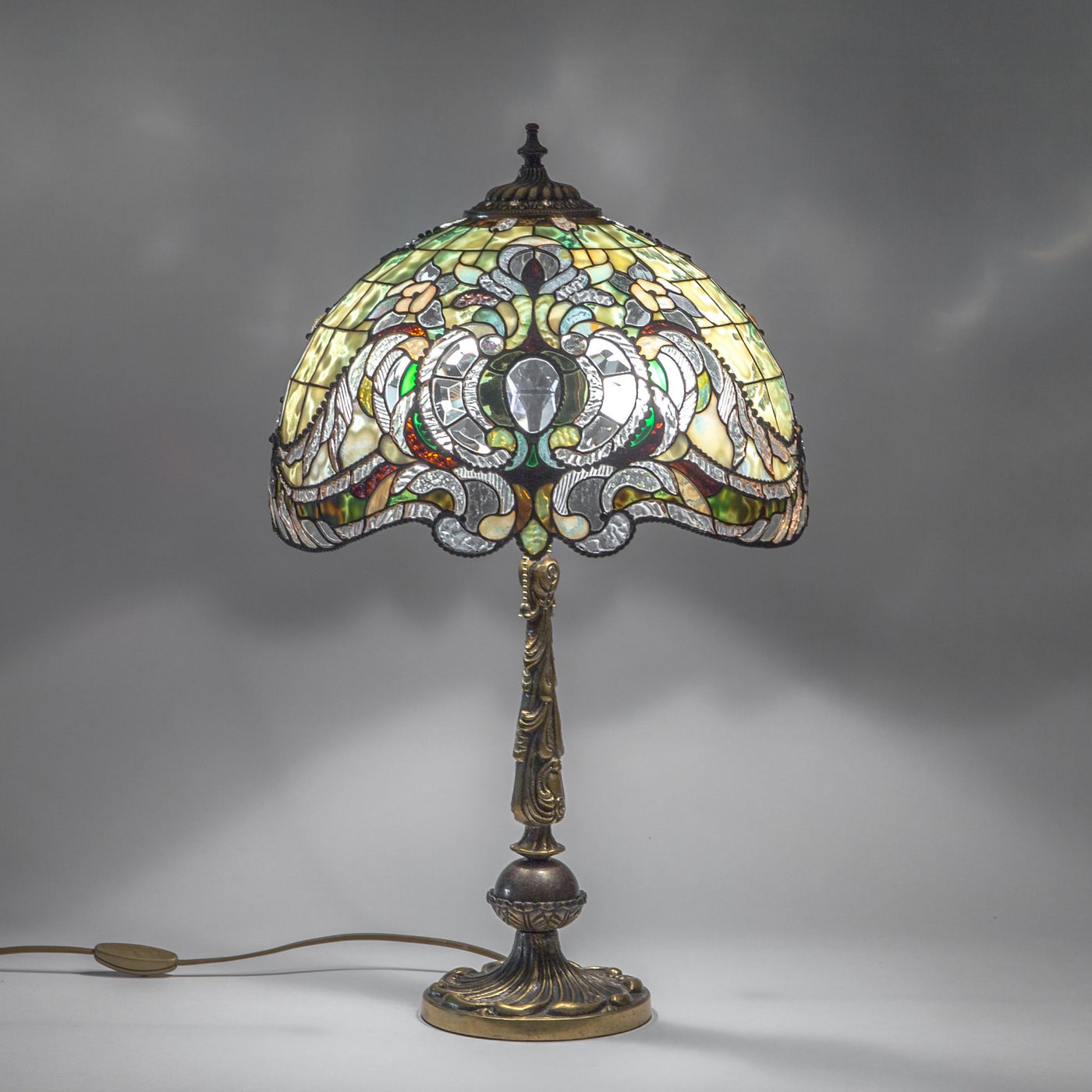 Lit stained glass green Tiffany lampshade with bronze base with engraving
